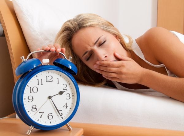 Schlaflosigkeit mit Uhr in der Nacht. Frau kann nicht schlafen.