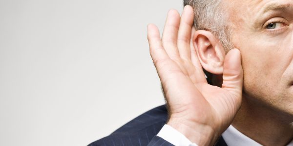 Man in suit cupping his ear with his hand