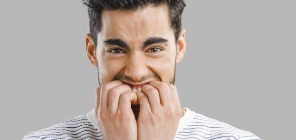 Close-up portrait of a worried young man biting nails